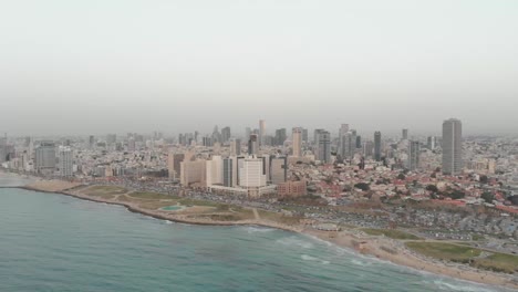Aerial-view-of-Tel-aviv-beaches-and-charles-clore-park-at-sunset,-Summer-time-with-haze-in-the-air-1