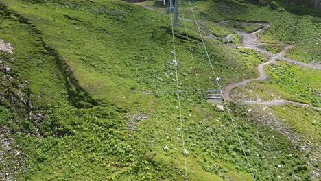 A-drone-follows-a-cable-car-going-up-the-mountain,-gondola-ascent-in-the-swiss-alps,-Obwalden,-Engelberg,-drone-aerial-top-view