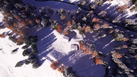 Cabin-building-covered-in-white-snow-in-remote-mountain-valley,-top-down