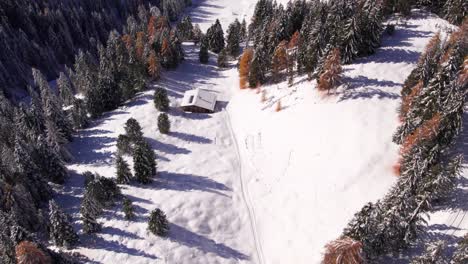 Val-Gardena-valley-with-remote-mountain-cabins-during-winter-season,-aerial