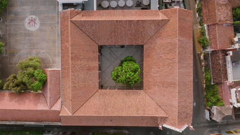 Aerial-pedestal-shot-of-a-tree-in-the-middle-of-a-courtyard-of-a-building-in-Old-Town-Cartagena,-Colombia