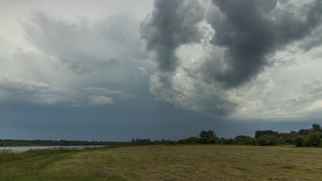 Zeitraffer-Der-Dramatischen-Wolken,-Die-über-Die-Wiese-Und-Den-Fluss-Ziehen