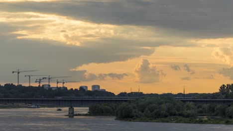 Zeitraffer-Mit-Kränen-Auf-Der-Baustelle-Unter-Den-Sich-Schnell-Bewegenden-Wolken-Während-Des-Sonnenuntergangs