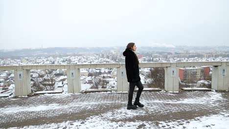 Attractive-young-female-model-walking-on-viewpoint-in-front-of-a-city-winter-day