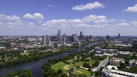 Austin-skyline-and-the-Colorado-river-in-sunny-Texas,-USA---tracking,-aerial-view