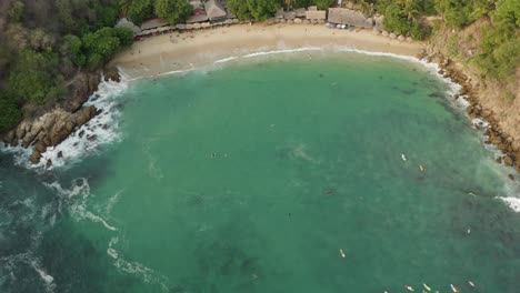 Drohnenaufnahme-Von-Playa-Carrizalillo,-Die-Vom-Schönen-Wasser-In-Die-Stadt-Und-Umgebung-Schwenkt