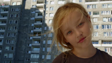 Girl-portrait-face-in-front-of-block-of-flats,-expensive-own-housing-for-people,-low-angle-view