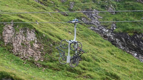 Transportes-De-Bicicletas-Por-Telesitio-En-Los-Alpes-Suizos,-Montaña-Escarpada-Detrás,-Obwalden