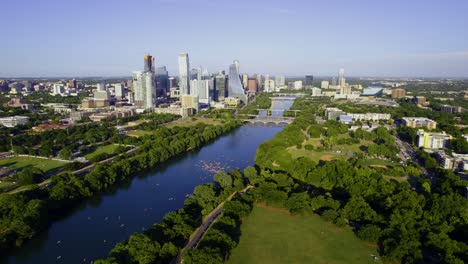 Austin-skyline-and-the-Colorado-river-in-sunny-Texas,-USA---pull-back,-aerial-view