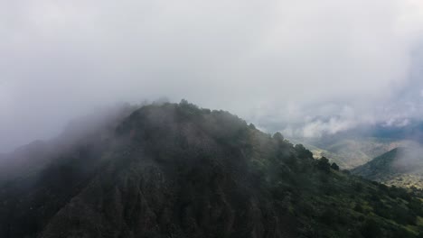 Aerial-shot-of-hill-covered-in-cloudy-mist