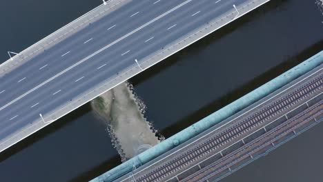 Vista-Aérea-De-Arriba-Hacia-Abajo-De-La-Carretera-Del-Puente-Sobre-El-Río,-Infraestructura-De-La-Ciudad