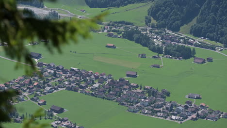 Engelberg-village-with-grass-meadows-and-fir-forests-view-from-a-mountain-beside-it,-Obwalden