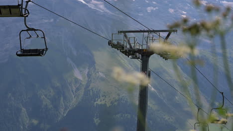 Instalación-De-Telesilla-En-Los-Alpes-Suizos-Con-El-Poste-Y-Las-Flores-En-Primer-Plano,-Obwalden,-Engelberg