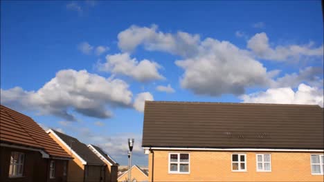 A-time-lapse-of-clouds,-various-shapes-and-colours-passing-over-houses-in-England,-United-Kingdom