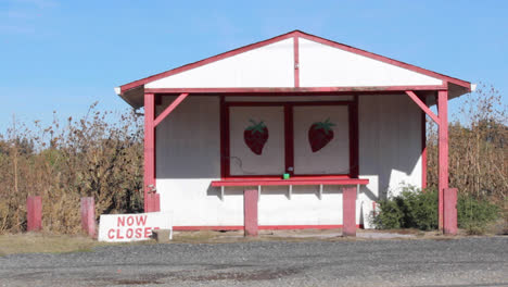 Car-drives-by-closed-roadside-fruit-strawberry-stand-in-Butte-County,-California