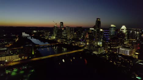Aerial-view-of-a-Illuminated-downtown-Austin-and-a-calm-river,-dusk-in-Texas,-USA