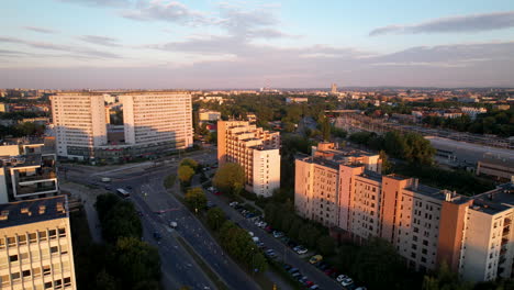 Ascending-drone-shot-of-district-in-krakow-with-apartment-complex-blocks-lighting-in-sun-at-sunset