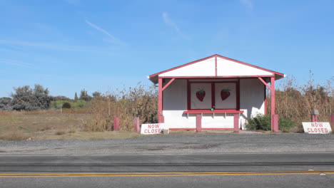 Truck-drives-by-closed-roadside-fruit-strawberry-stand-in-Butte-County,-California