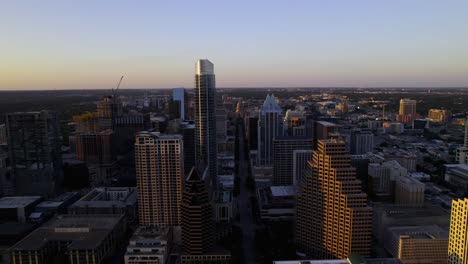 Aerial-view-flying-between-buildings-on-the-Congress-Ave,-towards-the-Texas-state-capitol,-sunset-in-Austin,-USA