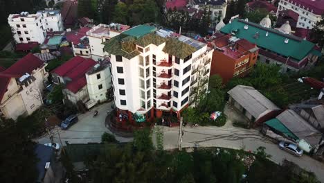 A-descending-aerial-shot-focusing-on-a-small-apartment-block-reveals-a-larger-Asian-neighbourhood