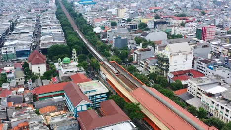 Above-ground-metro-train-system-in-a-dense-urban-neighborhood-of-Jakarta-Indonesia,-aerial