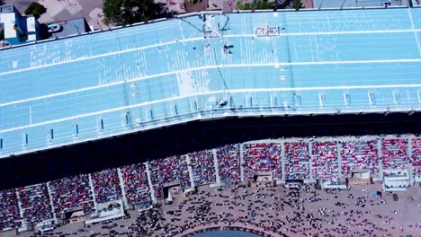 Vogelperspektive-Von-Oben-Zeigt-Die-Haupttribüne-Des-Stadions,-Auf-Der-Sich-Rodeo-Künstler-Präsentieren,-Während-Die-Menge-Ihnen-Zujubelt,-Wenn-Sie-Sich-Laut-Und-Stolz-Dem-Tribünenpublikum-Nähern