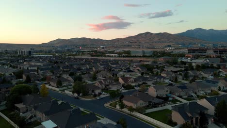 Suburban-neighborhood-at-sunset-with-business-offices-on-the-foothills-of-the-mountains---aerial-flyover
