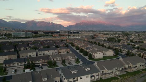 Sliding-aerial-panoramic-view-of-a-suburban-neighborhood-at-sunset-in-a-valley-under-the-mountains