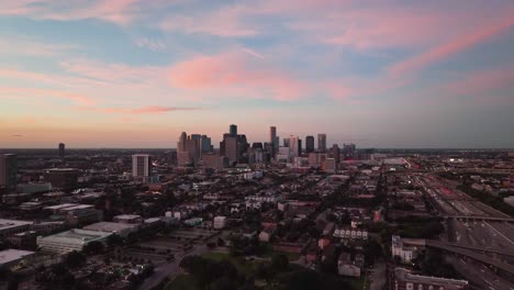 Aerial-view-approaching-downtown-Houston-skyscrapers,-vibrant-dusk-in-Texas,-USA