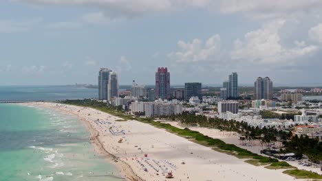 Tropical-sandy-beach-of-Miami-with-majestic-downtown-buildings-on-horizon