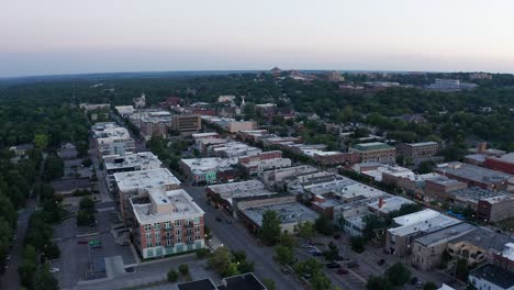 Aerial-dolly-shot-flying-over-Massachusetts-Street-in-downtown-Lawrence,-Kansas-at-sunset