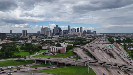 Aerial-view-over-traffic-towards-the-Houston-skyline,-cloudy-USA---rising,-drone-shot