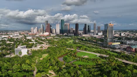 Aerial-view-overlooking-the-Eleanor-Tinsley-Park-with-Houston-skyline-in-the-background,-sunny,-summer-evening-in-USA---pull-back,-drone-shot