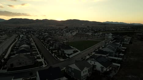 Sunset-behind-the-mountains-with-a-picturesque-suburban-neighborhood-in-the-valley---aerial-parallax