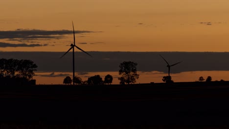 Lapso-De-Tiempo-Siluetas-De-Turbinas-Eólicas-Que-Generan-Electricidad-Contra-Un-Cielo-Dorado-Al-Atardecer