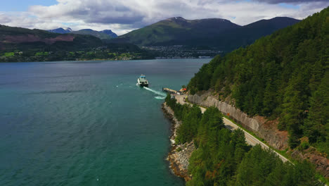 Aerial-view-of-a-car-transport-ferry-leaving-the-Liabygda-Feriekai-in-central-Norway---ascending,-drone-shot