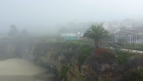 Aerial-View-of-Morning-Fog-Above-Laguna-Beach,-Beachfront-Resort-and-Pacific-Ocean,-California-USA