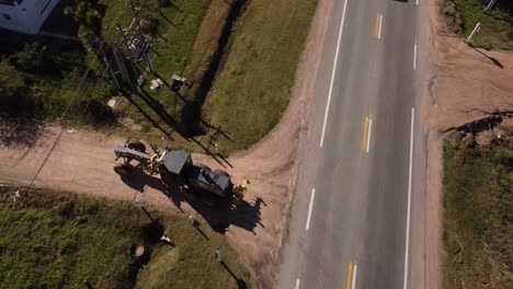 Aerial-tracking-shot-of-rolle-vehicle-turning-into-construction-site-road-at-sun