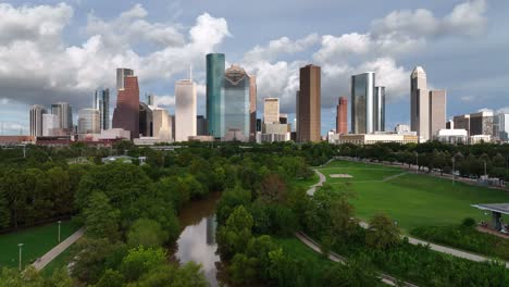 Aerial-view-rising-over-the-Buffalo-bayou-river,-towards-skyscrapers-in-Houston-city