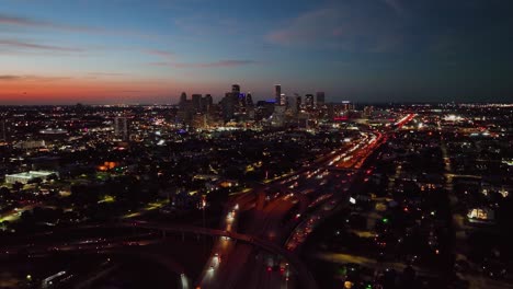 Luftaufnahme-In-Richtung-Der-Beleuchteten-Nachtskyline-Von-Houston-City,-Dämmerung-In-Texas,-Usa