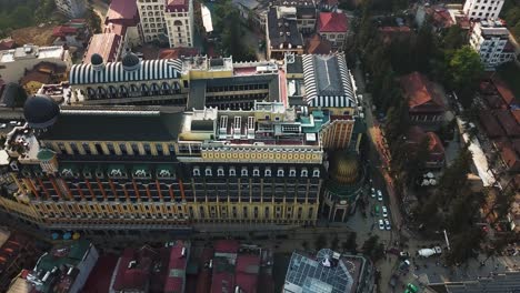 -Aerial-shot-flying-over-the-top-of-an-ornate-hotel-building-reveals-an-internal-courtyard-and-rooftop-swimming-pools