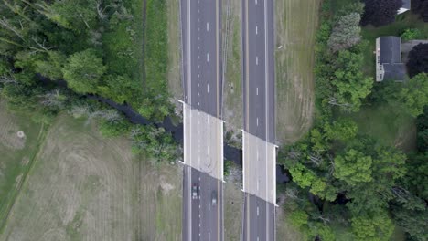 Aerial-drone-bird's-eye-view-over-two-over-birdges-over-a-water-canal-along-a-highway-at-daytime