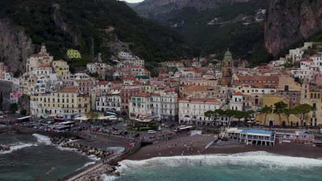 Historic-Town-of-Amalfi-below-Cliffs-on-Italy-Coast,-Aerial-Establishing
