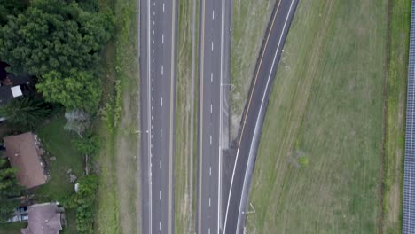 Aerial-drone-bird's-eye-view-over-highway-running-over-town-roads-during-evening-time