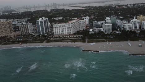 Miami-Beach-at-sunrise,-buildings,-sea-and-white-sand