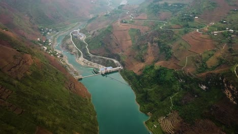 Zoom-in-aerial-shot-of-a-turquoise-colored-reservoir-and-dam-in-North-Vietnam