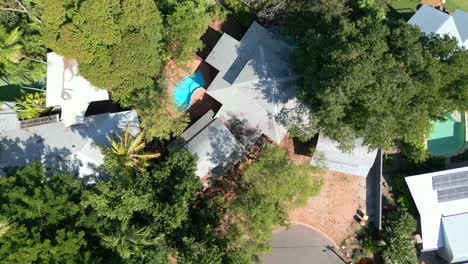 Top-down-drone-shot-of-houses-with-pools-at-the-end-of-a-quiet-street