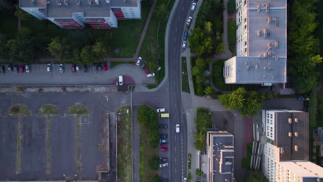 Aerial-top-down-shot-of-car-driving-on-road-between-residential-area-with-block-complex-in-Cracow