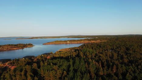 Aerial-view-over-forest-and-the-rocky-coast-of-Geta,-in-north-Aland,-summer-evening-in-Finland---rising,-drone-shot