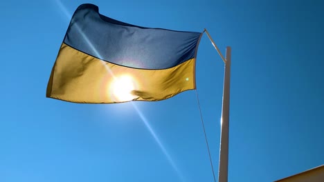 Ukrainian-flag-waving-in-the-wind-against-harsh-sun-light,-slow-motion-50fps